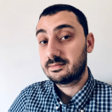 Professional headshot of Mihail Gabriel Subtirelu, wearing a blue check shirt against a light background.
